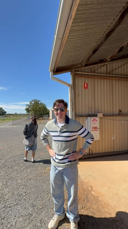 Team member beside farm buildings on a sunny gravel yard