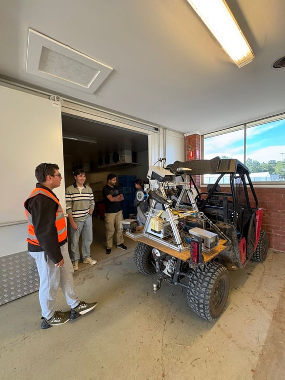 Team beside a modified utility vehicle with sensor rack in a workshop bay