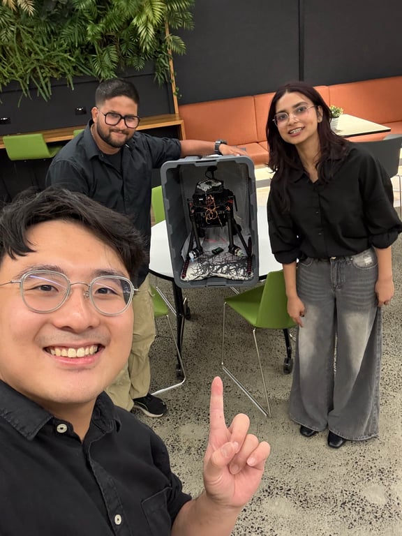Three teammates with a robotics prototype in a transport bin indoors