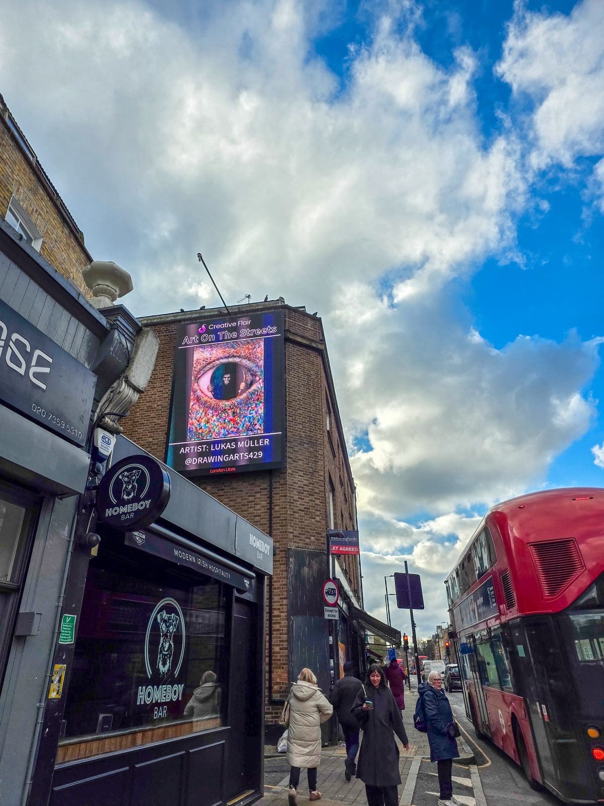 Lukas Muller posing beside his artwork featured on the London Art Fair billboard showcase - artist with billboard art exhibition on Essex Road during art fair week