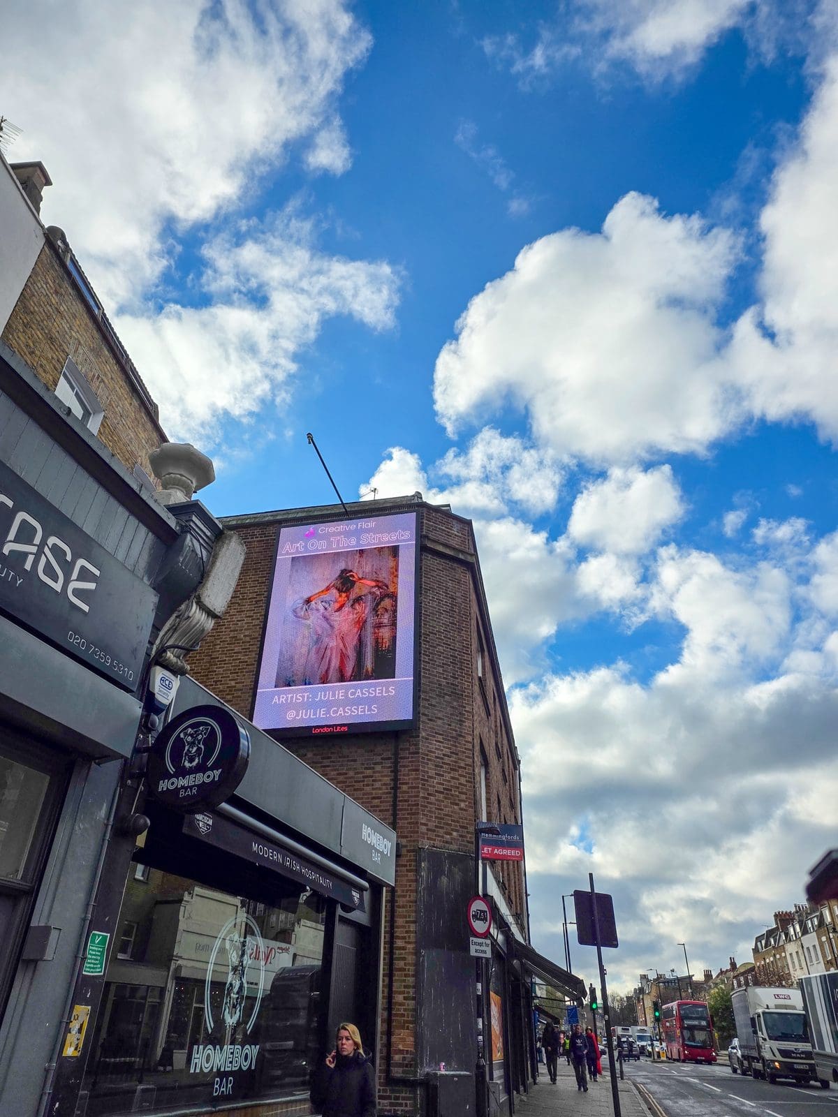 Julie Cassels standing in front of her billboard artwork during London Art Fair Edition - Art On The Streets artist at Essex Road digital screen