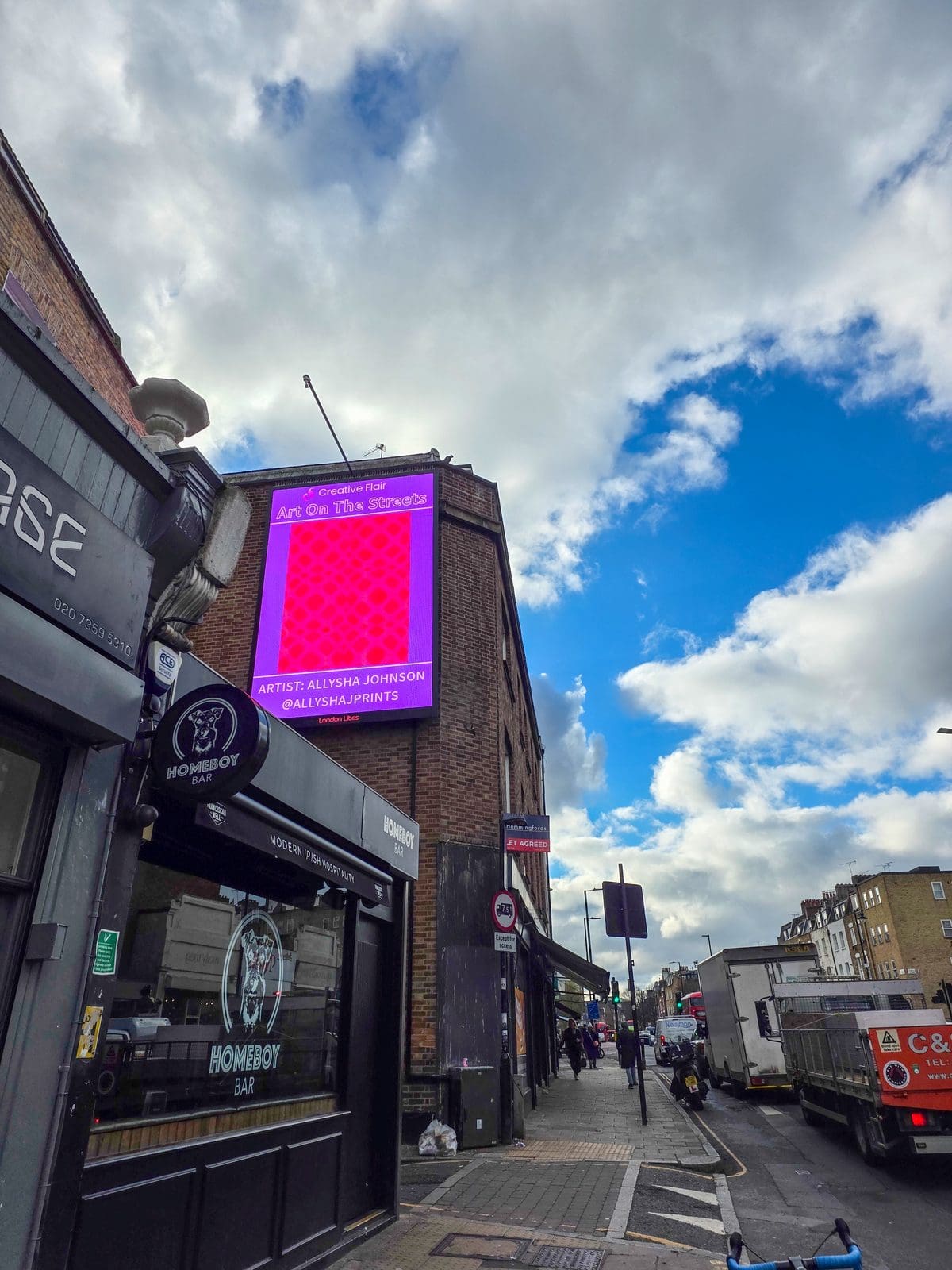 Allysha Johnson posing beside her featured artwork on the London Art Fair billboard - Art On The Streets artist billboard exhibition Essex Road during art fair opening day