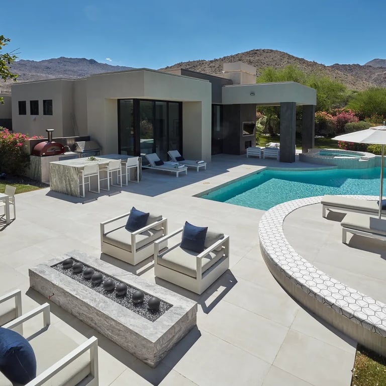 Fantasy Brown Polished marble on counters and firepit, Reside Beige 24 x 48 R11 Finish porcelain on patio floor, Reside Beige Straight Stack 1 x 12 Straight Stack porcelain on waterline & Geo 2 Metro Uptown glass tile on pool accent in outdoor patio.