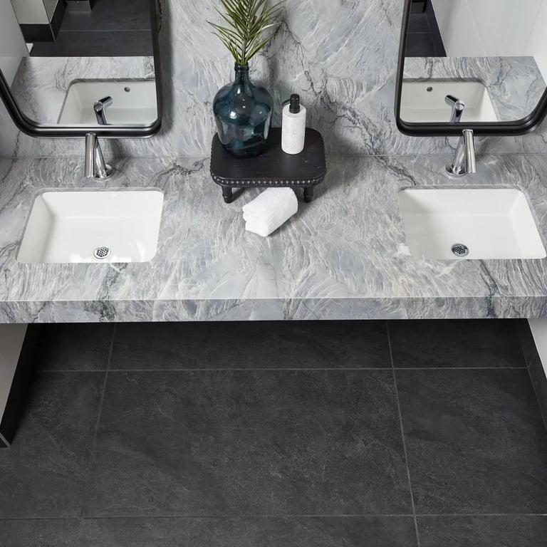 Blue Tahoe Satin quartzite on vanity & backsplash, Themar Bianco Lasa Polished 24 x 24 porcelain tile on left and right wall & Ardesia Black 24 x 48 porcelain tile on floor & trim on left wall in bathroom.