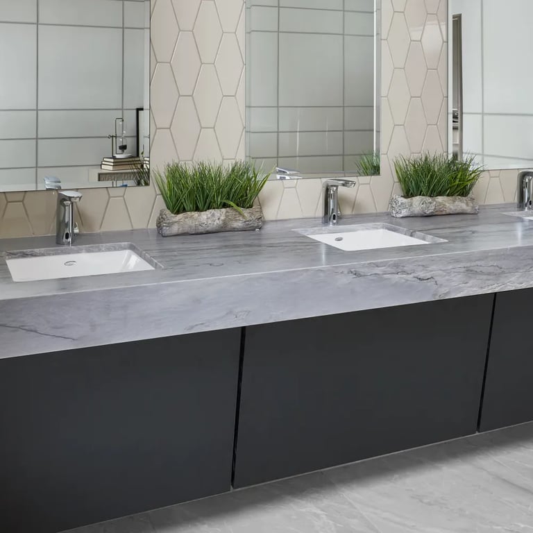 Blue Tahoe Satin quartzite counter, Paloma Pumice Long Hex ceramic tile (backsplash), Vetri Fume 24 x 24 and 8 x 24 porcelain tile on right wall & Tru Marmi Silver Matte 24 x 48 porcelain tile on the floor in commercial bathroom