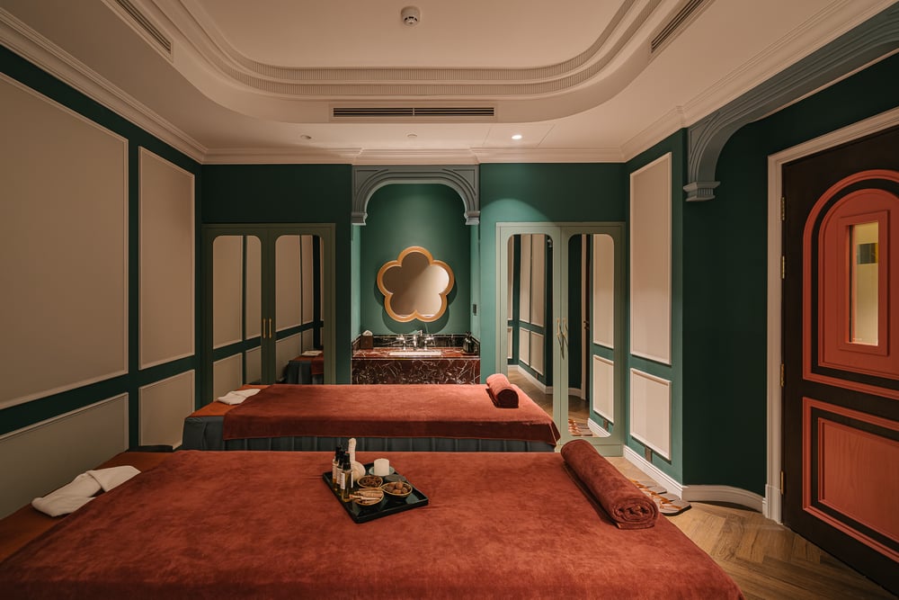Treatment room with a scalloped mirror and red lacquer door