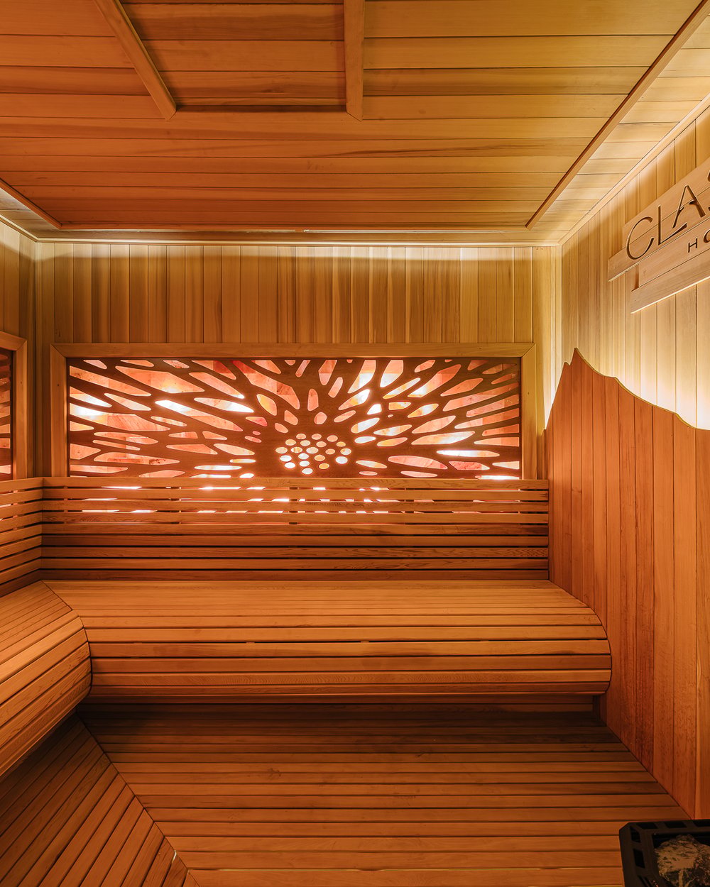 The sauna with its backlit carved panel and wooden benches