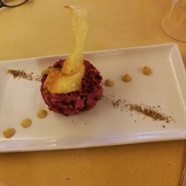 菜肴“Tartare di tempeh, capperi, cetrioli, rape rosse, senape ed erba cipollina con cialde di pane fritto”的照片