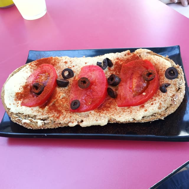 Foto do prato “Tostada de hummus, tomate y olivas”