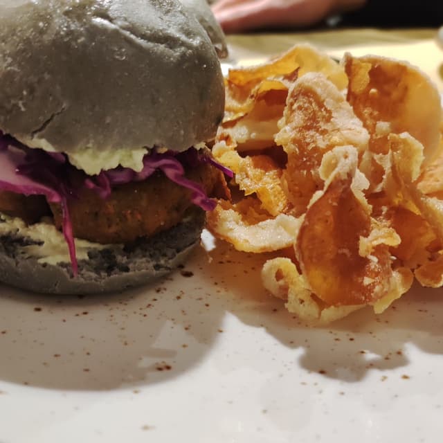 Foto del plato “Bao Buns Al Carbone Vegetale Con Burger Di Tempeh, Mayo Al Coriandolo, Insalatina Di Cavolo Viola E Chips Di Patata Dolce”