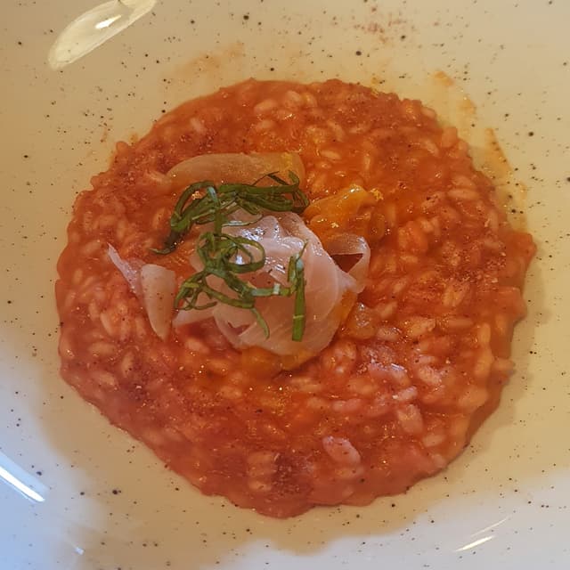 「Riso Carnaroli Riserva San Massimo mantecato alla Dolcissima di Breme, pesche e basilico」の料理の写真