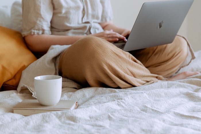 woman sitting on the bed with laptop and coffee