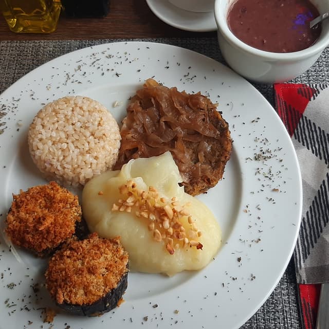Photo of the dish “Hambúrguer de legumes acebolado, arroz cateto integral,  feijão vermelho, purê de batata com amendoim, berinjela crocante.”
