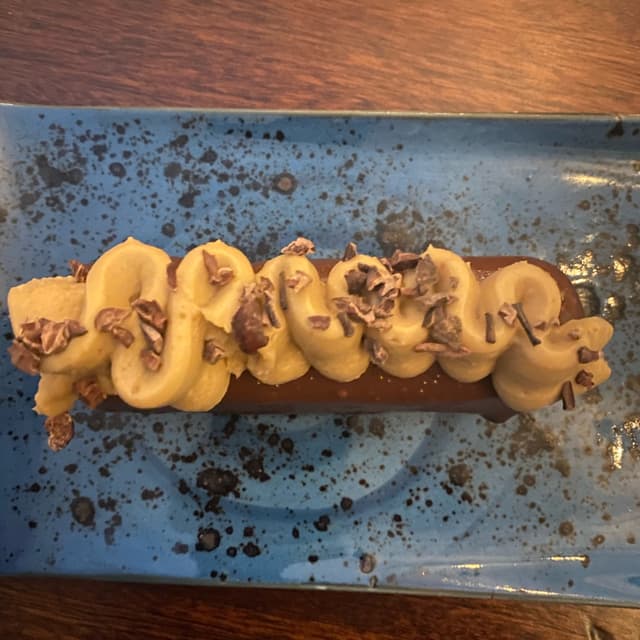 Foto del piatto “Churro de chocolate, avellanas, plátano y pasión”