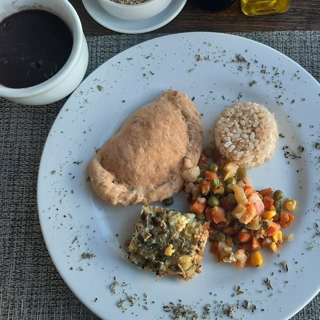 Photo of the dish “Arroz Cateto Integral, Feijão Preto, Torta De Abobrinha, Jardineira De Legumes E Galzone De Tofu, Palmito E Azeitona.”