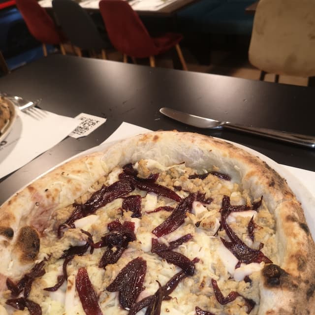 菜肴“Pizza con Vuna formaggio vegano e cipolla rossa caramellata”的照片
