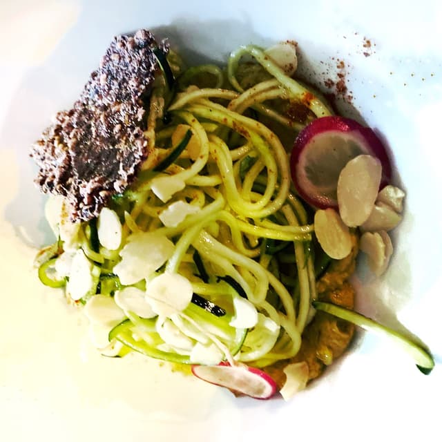 菜肴“Raw - spaghetti di zucchine con guacamole e mandorle con chips di riso nero soffiato”的照片