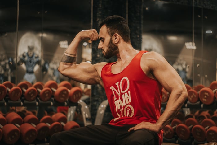 man in red gym wear flexin' his muscles