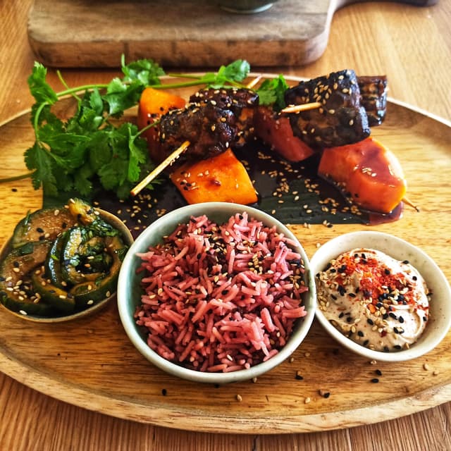 Photo of the dish “Tempeh Casero Y Orgànico A La Brasa Con Papaya, Arroz Basmati, Ensalada De Pepinos Y Salsa De Cacahuetes.”