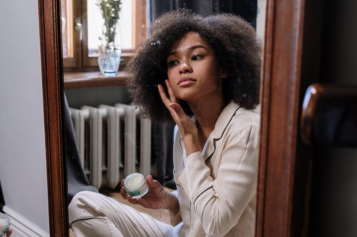 woman looking in mirror and applying face cream