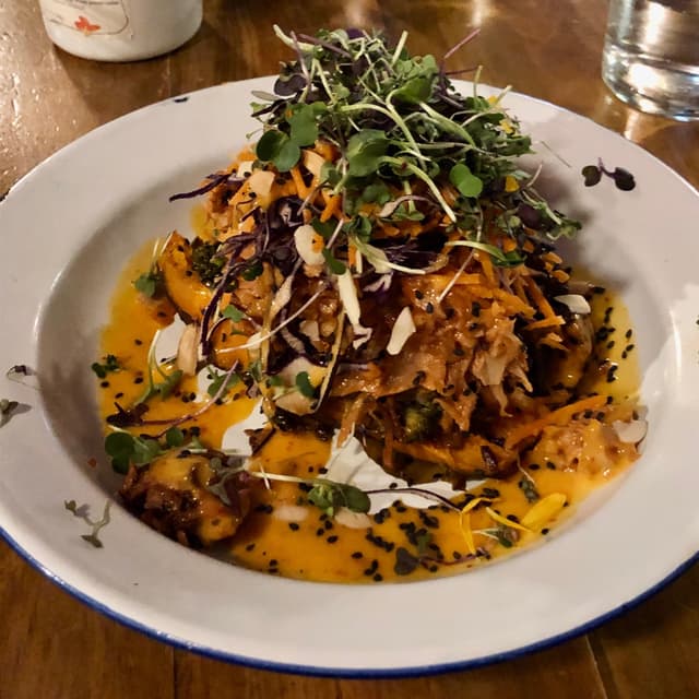 菜肴“Boniato asado relleno de Verduras estofadas, Almendras Tostadas, Soja Texturizada, Sésamo Negro Y Salsa Dulce Vegana.”的照片