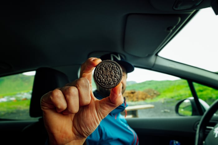 man in car holding up an Oreo