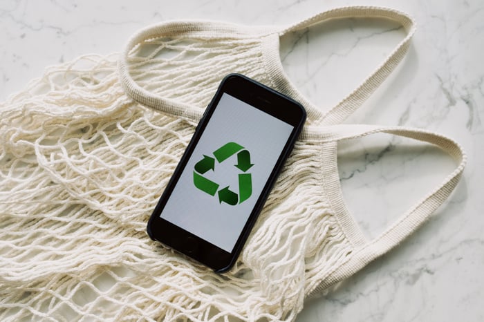 smartphone with recycle logo placed on top of a cloth bag