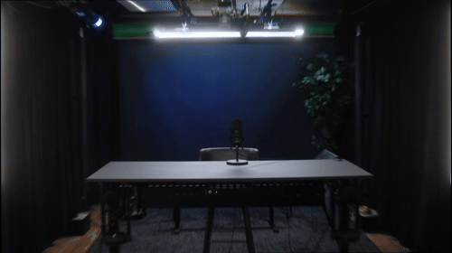 forum_update __ Studio de podcast avec une table, un microphone et un éclairage sombre.