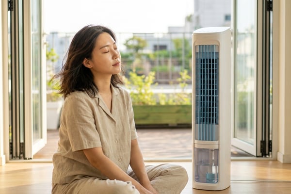 베란다 문을 활짝 연 거실에서 타워형 냉풍기 바람을 쐬는 한국인 여성