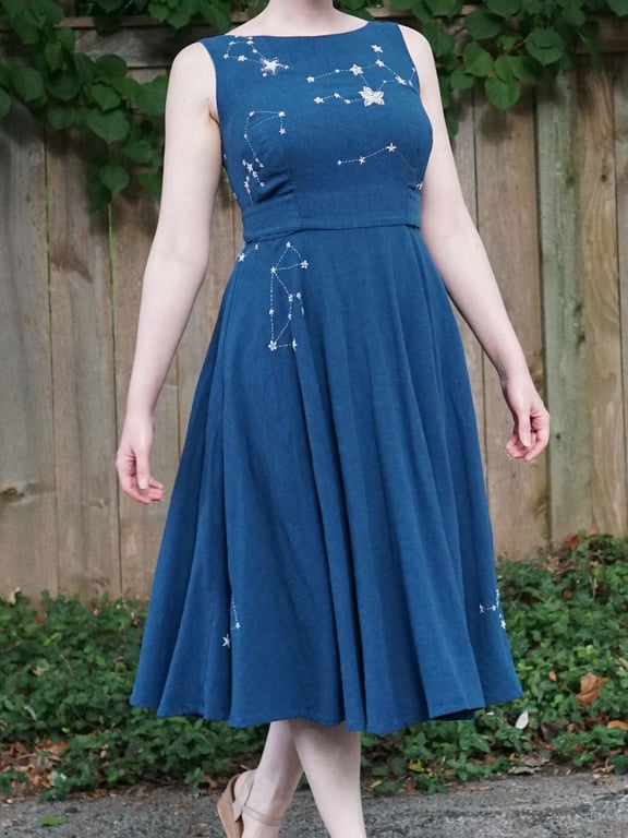 Une robe ajustée et évasée d'un bleu profond ornée de constellations en broderie.