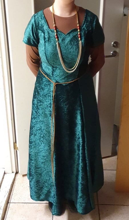 The evening gown, styled with a thin leather string belt, red-gold necklace and a brown shirt underneath for a medieval look.