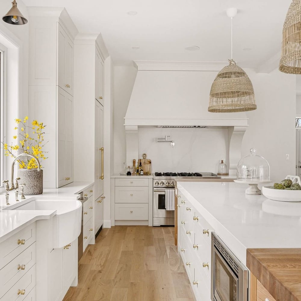 Bright modern kitchen featuring white cabinetry, a large island, and decorative pendant lighting.