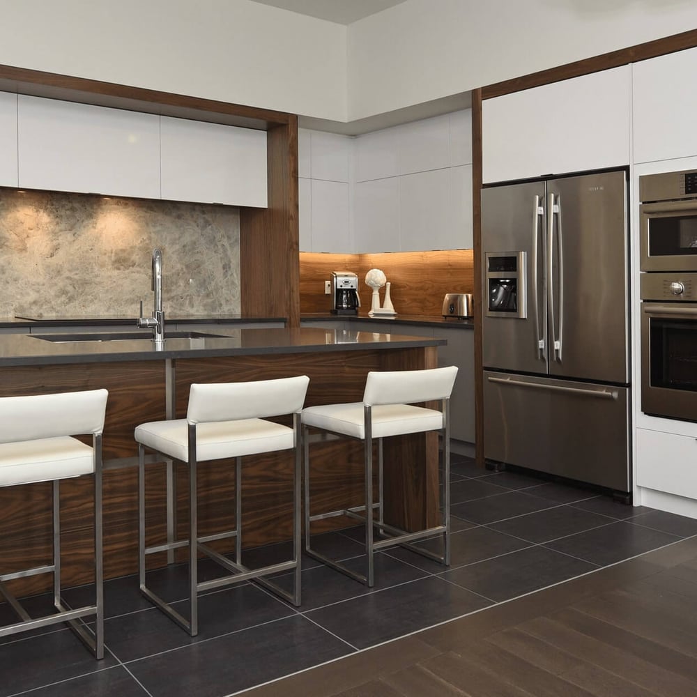 Callingham kitchen by Casey's Kitchens with high-gloss white cabinets, walnut accents, marble backsplash, and stainless steel appliances in a modern London, Ontario space.