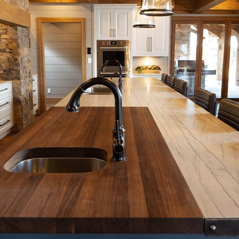 Project_Kitchens_Fruit+Ridge7 Wooden kitchen island with a sink and a marble countertop, featuring modern fixtures and a spacious design.