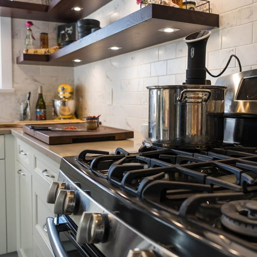 Project_Kitchens_Old+South10 Old South Kitchen project by Casey's Kitchens with a stainless steel gas range, large pot on the stove, white subway tile backsplash, and dark walnut floating shelves.