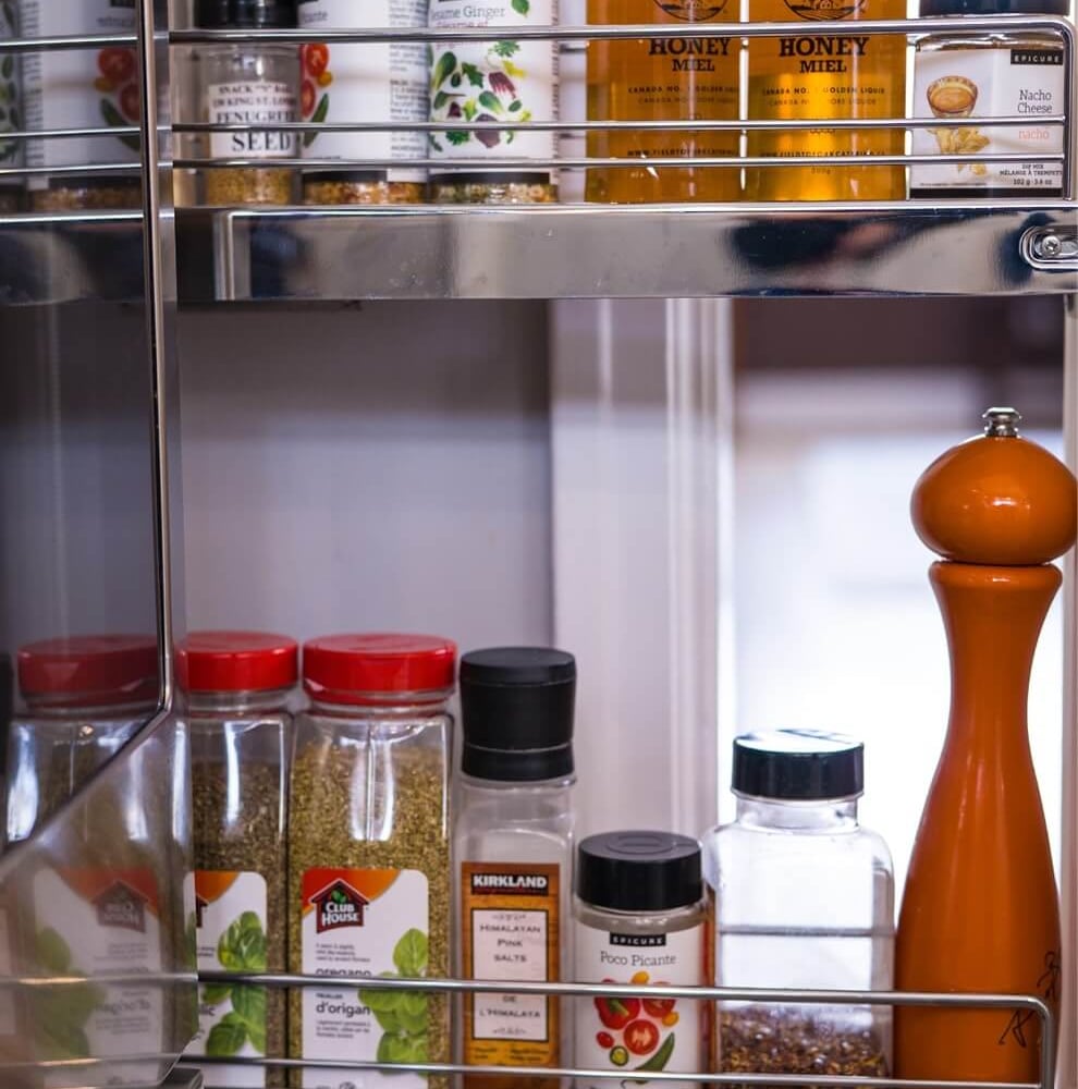 Project_Kitchens_Old+South11 Old South Kitchen by Casey's Kitchens with spice jars, honey jars labeled Field To Fork, and a tall orange pepper mill on a chrome pull-out rack in a compact 75 sq ft space
