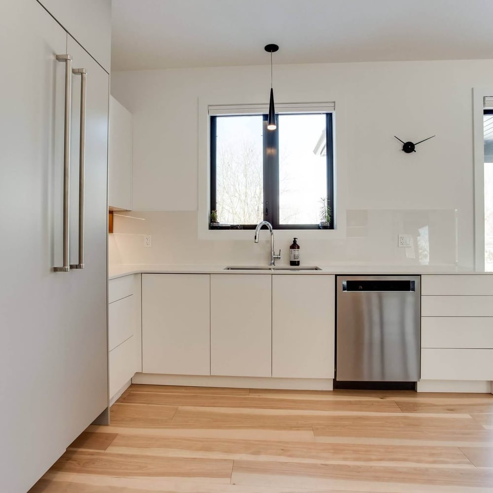 eMg9qin0 Modern kitchen with white cabinetry, stainless steel dishwasher, and large windows providing natural light.