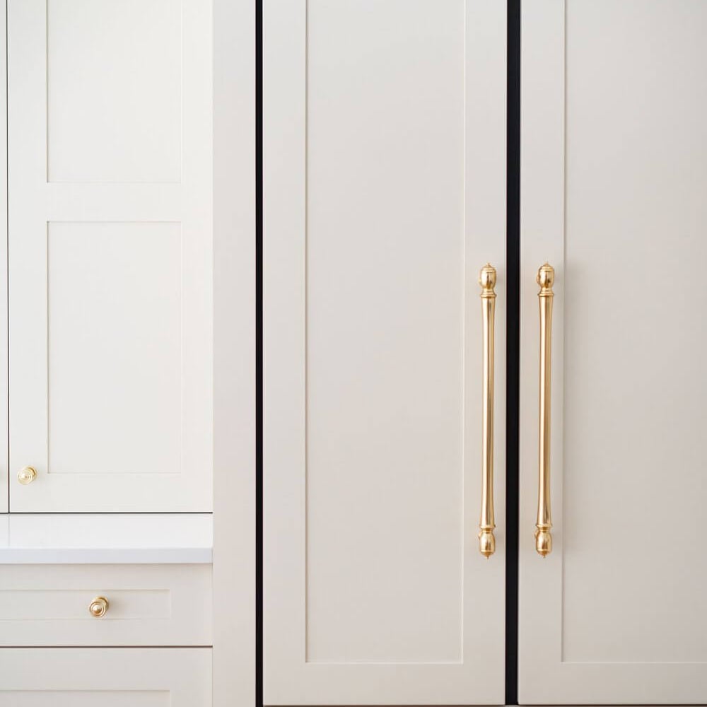 A modern kitchen refrigerator with a sleek design and gold handles, featuring a light grey finish.