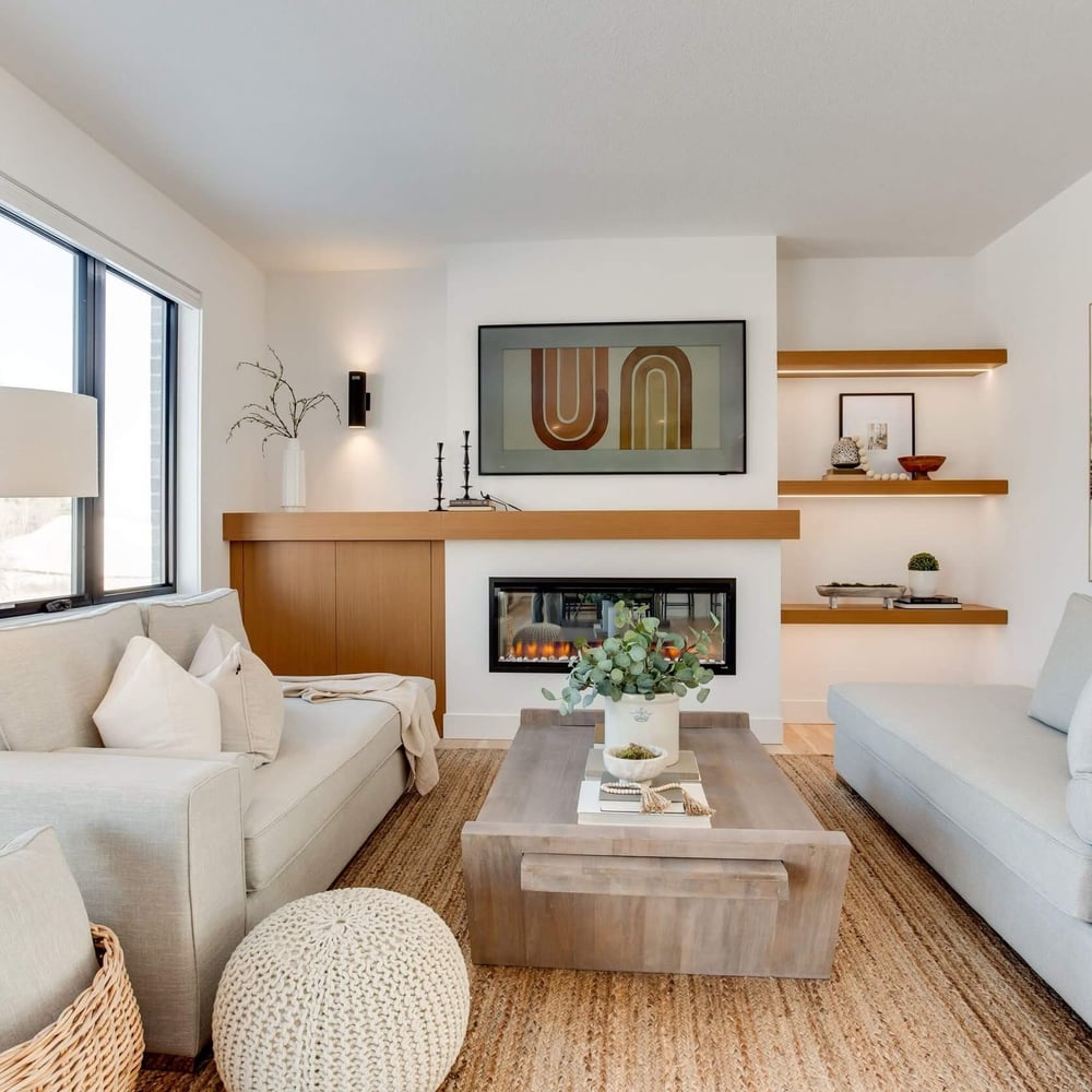 gRZ268bU Modern living room with two light gray sofas, a wooden coffee table, and a wall-mounted fireplace, featuring decorative shelves and artwork.