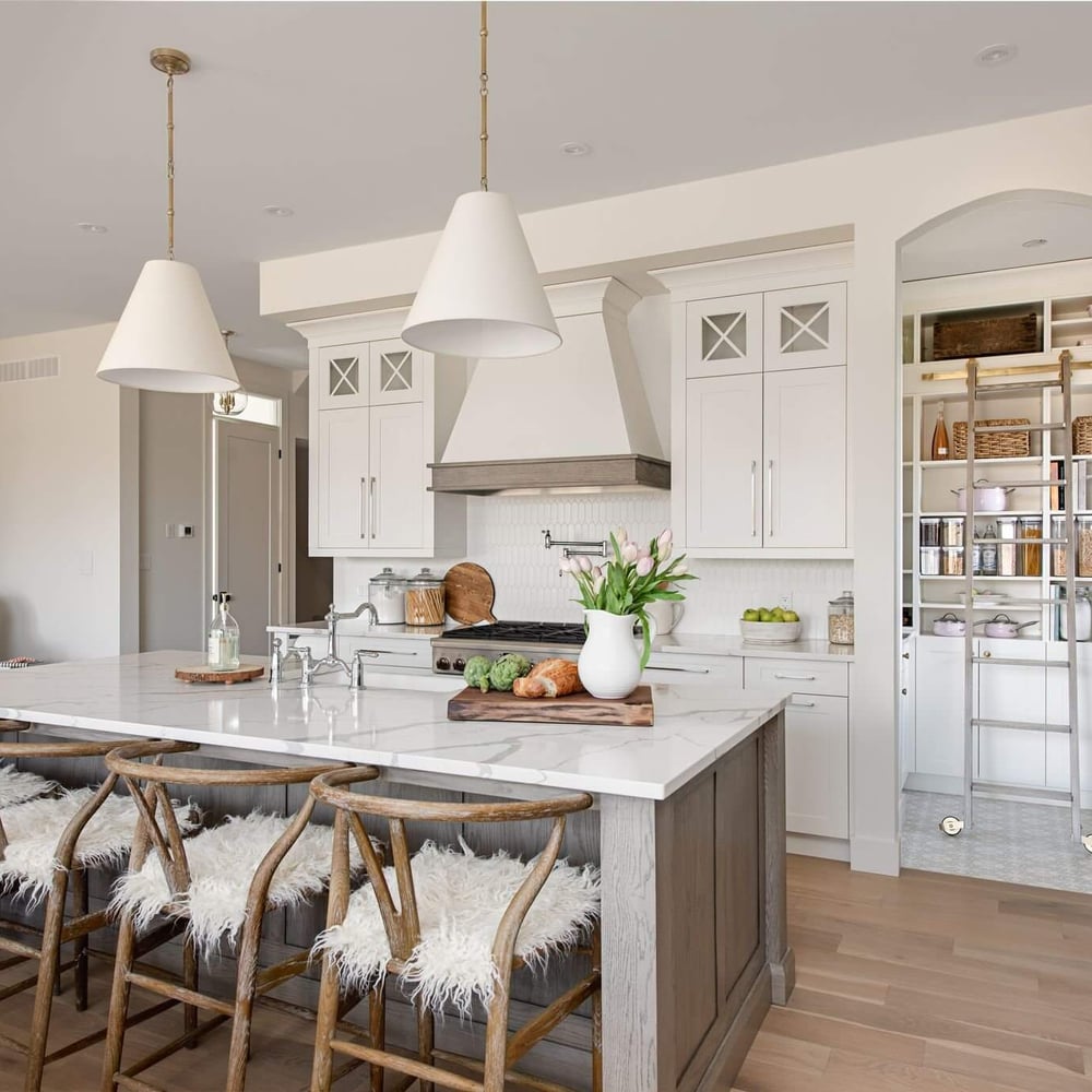 Byron Beauty kitchen by Casey's Kitchens with muted white cabinetry, oak accents, a marble island, and brass hardware in a modern French Country style, located in London, Ontario