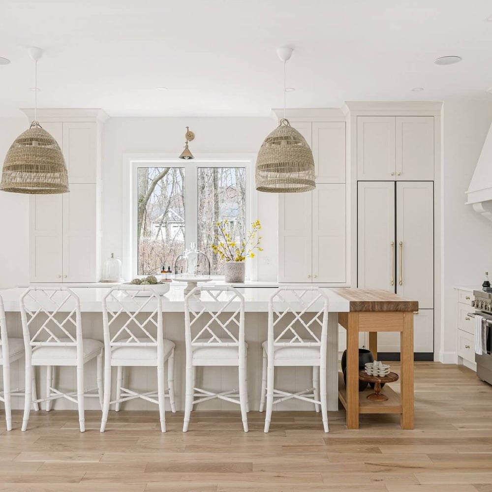 Modern kitchen featuring white bar stools, pendant lights, and a large island with a wooden countertop.