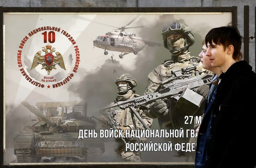 Men walk past a military poster dedicated to the National Guard in St. Petersburg, Russia, 13 March 2026. Photo: EPA/ANATOLY MALTSEV