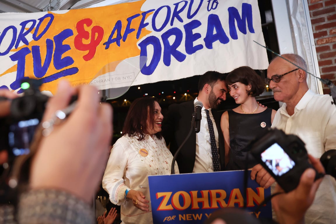 Зохран Мамдани (в центре справа) выходит на сцену со своей семьёй — матерью, режиссёром Мирой Наир (слева), женой Рамой Дуваджи и отцом, историком Махмудом Мамдани (справа) — во время вечеринки по случаю победы на праймериз, Нью-Йорк, США, 25 июня 2025 года. Фото: AP Photo / Heather Khalifa / Scanpix / LETA