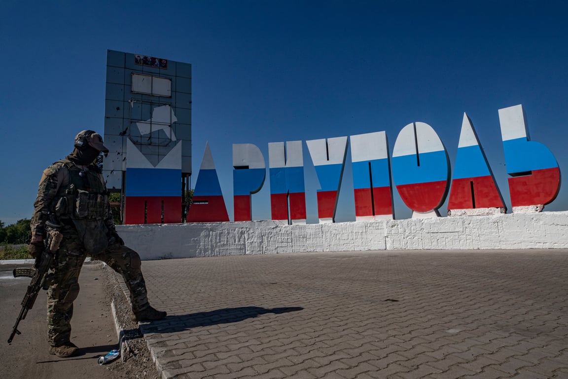 Российский военнослужащий у перекрашенной в цвета российского флага стелы «Мариуполь» на въезде в город, Донецкая область, Украина, 12 июня 2022 года. Фото: Сергей Ильницкий / EPA