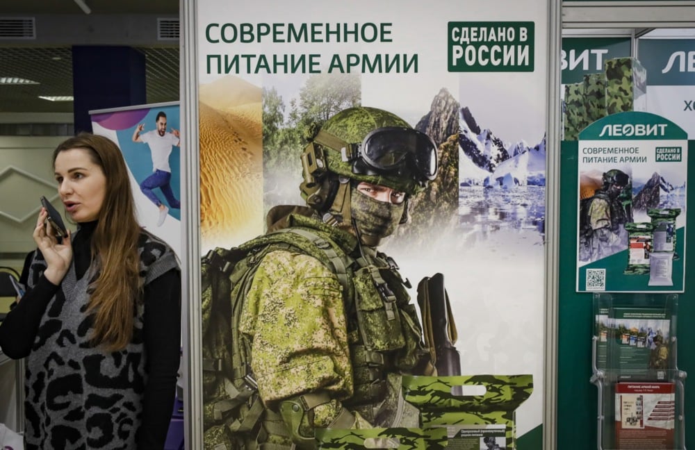 A woman speaks on the phone next to a military-themed banner in Moscow, Russia, 16 December 2022. Photo: EPA/YURI KOCHETKOV