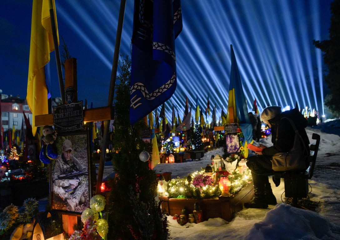 Инсталляция «Лучи памяти» освещает небо над Лычаковским военным кладбищем во Львове во время поминальной молитвы и акции со свечами, 23 февраля 2026 года. Фото: Mykola Tys / EPA