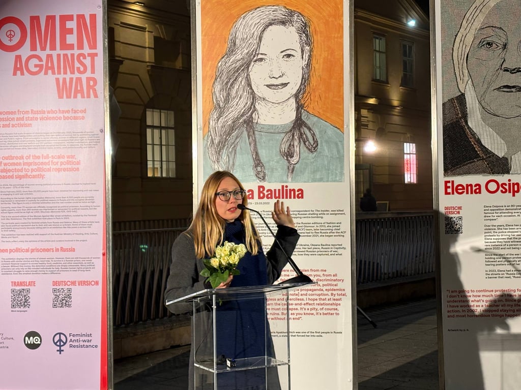 Дарья Апахончич у портрета Оксаны Баулиной. Фото: Тая Рехова / специально для «Новой газеты Европа»