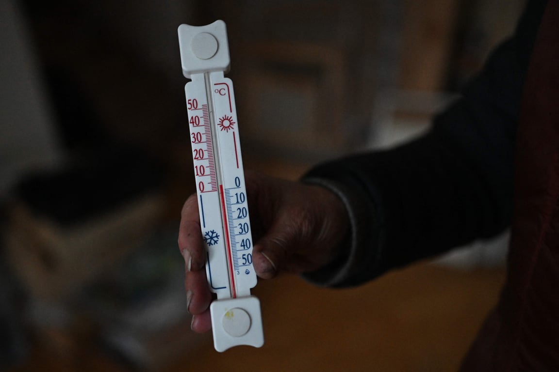 Жительница Киева показывает термометр с температурой в доме, Украина, 25 января 2026 года. Фото: Sergei Gapon / AFP / Scanpix / LETA