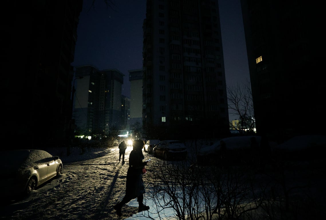 Люди идут с фонариками по тёмной улице во время отключения электроэнергии в Киеве, Украина, 9 января 2026 года. Фото: Sergey Dolzhenko / EPA