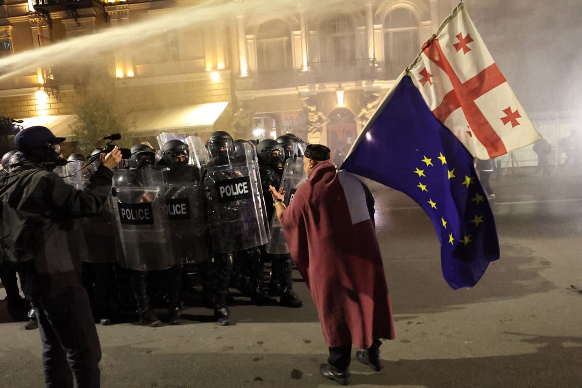 Протестующий с флагами Евросоюза и Грузии напротив грузинских силовиков, Тбилиси, Грузия, 4 октября 2025 года. Фото: Giorgi Arjevanidze / AFP / Scanpix / LETA